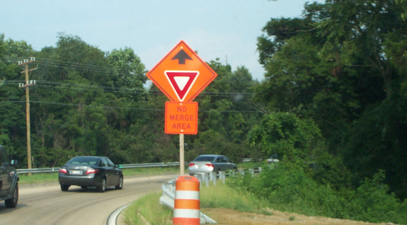 Yield sign, with words below it -No Merge Area-