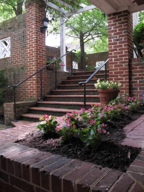 Flowers potted in a brick bench, surrounded by brick.  Also brick stairs and a trellis.