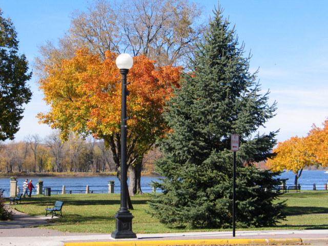 A river bordering LaCrosse, WI, with trees changing leave colors in the foreground.