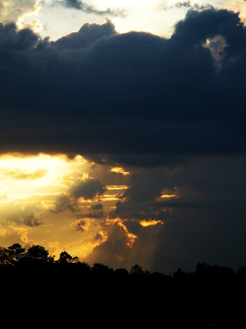 A sun setting behind massive rain clouds.