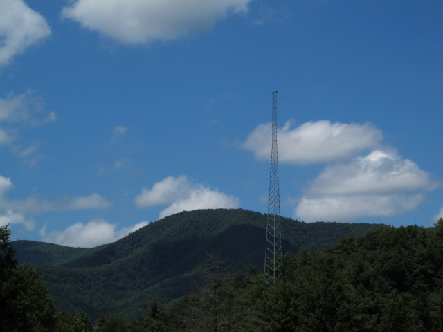 A radio tower with lots of greenery and hills and stuff.