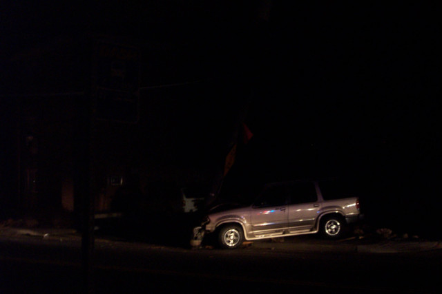 A low quality picture of an SUV crashed into a telephone pole.