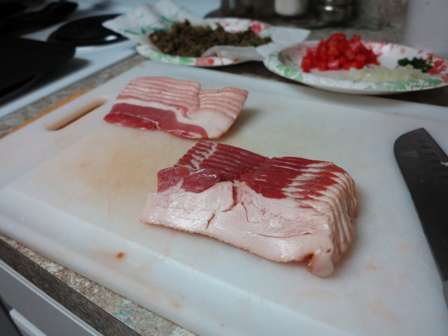 Raw bacon on a cutting board.