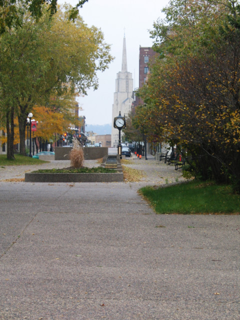 A public clock, foreground, tall building, background.