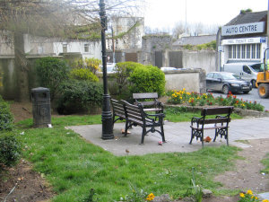 Public benches on a patio, and a trash can.