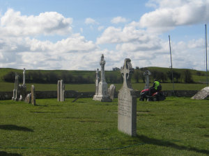 A guy mowing the lawn in a cemetary, at Clonmacnoise.